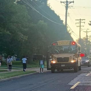  students walking to a bus picking them up from a stop